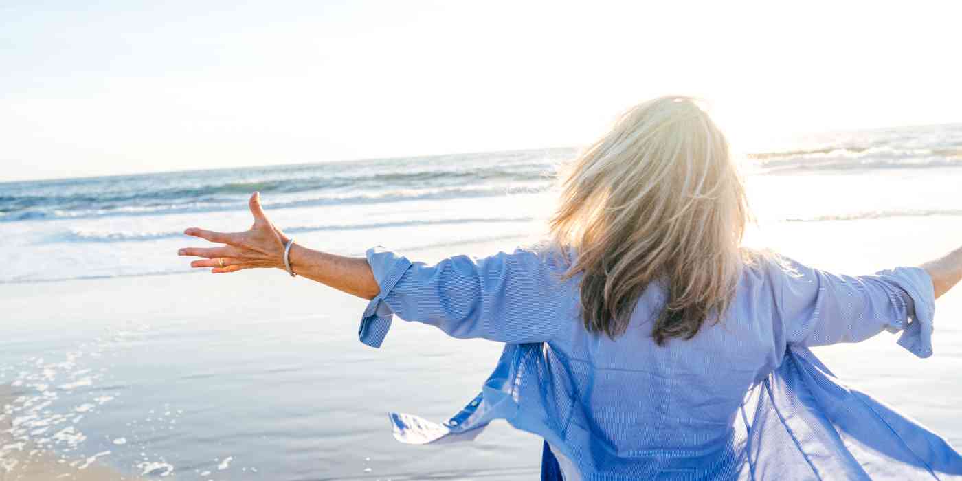 Binge eating disorder banner image depicted by woman excitedly gesturing at the ocean with wide open arms