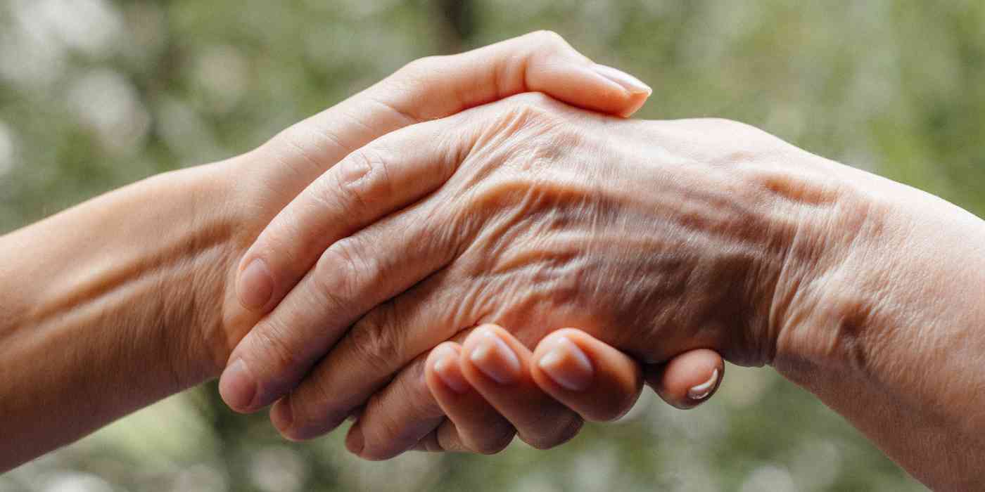 Senior counselling banner depicts a young person's hand holding a geriatric person's hand.