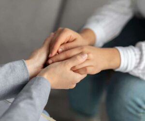 Compassionate therapist holds clients hands